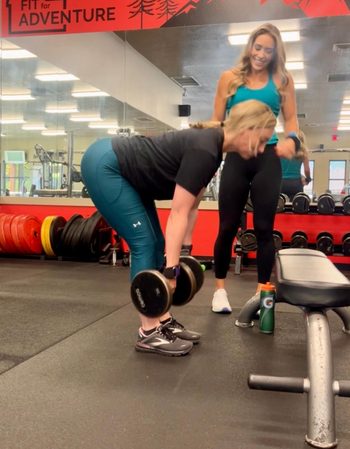 Female personal trainer Allie coaching a client how to deadlift during her in person session